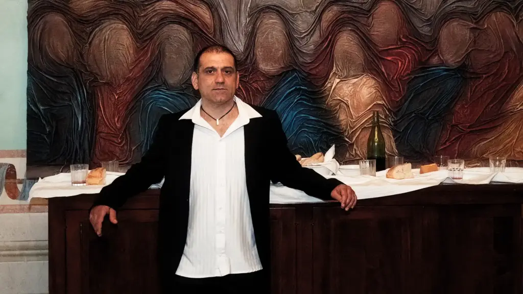 Ritratto dell'artista Bruno Florio davanti all'opera intitolata L'ultima cena